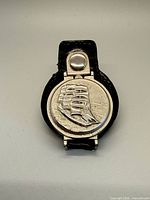 Front view of pocket watch in leather case showing raised ship relief