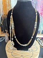 Full view of necklace on display bust showing gold-tone chains and faux pearls