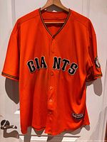 Front view of orange Giants jersey on hanger showing team lettering and sleeve patch