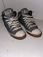 Front view of both shoes showing grey leather uppers, white toe caps, laces and Converse tongue labels