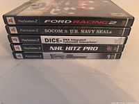 Stack of five PlayStation 2 game cases showing spines and titles