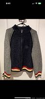 Full view of sweater on hanger showing color blocking and stripes