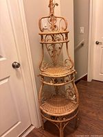 Full view of wicker corner shelf showing three tiers and scrollwork