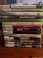 Stack of thirteen Xbox 360 game cases showing spines and titles