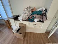 Overall view of piled curtains and linens on countertop with box below