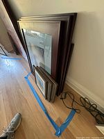 Stack of large and smaller frames leaning against wall