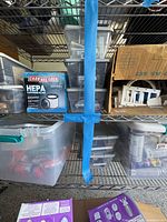 Shelf with Channelock HEPA filter box, clear bins, cardboard box of wall plates