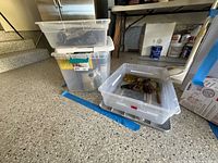 Stacked clear totes showing contents of paint, brushes and chisels