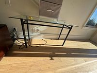 Glass table with metal frame and cords nearby