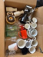 Top view of box showing mugs, wooden goblets, moka pot, vases, cups, saucers, glassware