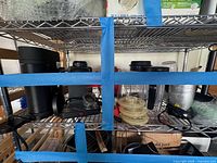 Shelf view showing Keurig coffee maker, NutriBullet base, cups, lids and other accessories