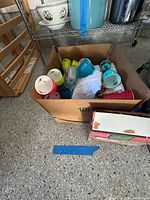 Cardboard box with visible colorful plastic tumblers and additional items