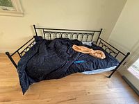 wide view of black metal daybed with bedding in place