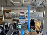 Full view of metal shelf with bins, tumblers, utensil holder, bags and boxes