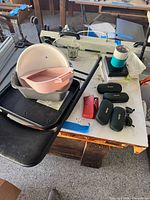 Wide view showing stacked plastic bowls, eyeglass cases, Ray-Ban sunglasses, travel mug on table