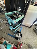 Full view of turquoise three-tier cart loaded with miscellaneous items