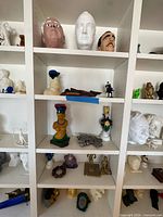 Full shelving view showing multiple 3D printed sculptures across five shelves