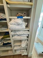 Full view of far-right column shelves with folded white sheets