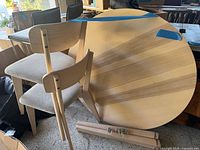 Round wooden tabletop, chairs and table legs visible