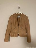 Front view of tan Guess leather jacket on hanger showing zippers and hem detail