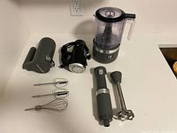 All components laid out: food chopper, hand blender pieces, hand mixer with beaters, whisk, charger