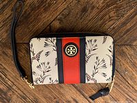Front view showing floral print, stripes, logo medallion, zipper and wrist strap