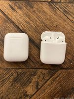 Two closed and one open Apple AirPods charging cases showing earbuds