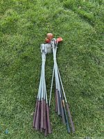 All golf clubs laid out on grass showing full length, heads and grips