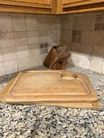 Two wood cutting boards stacked on countertop with wood knife block in background