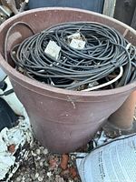 Top view of brown container showing coiled black coaxial cables and some white cables mixed with debris