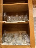 cabinet shelf with upper level of tumblers and a wine glass