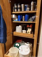 Cabinet with travel mugs, plastic mugs, sports bottles, containers, salad spinner and bowls