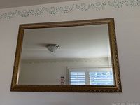 Front view of rectangular gold framed mirror on wall