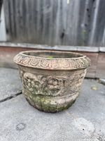 Front angled view of the Italian planter pot showing grape relief, patterned rim, moss patina