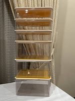 Front view of six stacked clear plastic boxes with yellow lids