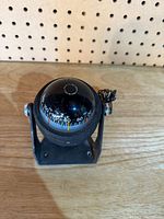 Front view of bracket-mount marine compass showing degree scale and dome