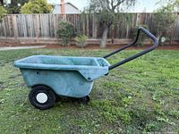 Side view of green plastic wheelbarrow on grass