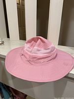 Overall view of pink wide-brim hat on railing