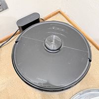 Top view of Roborock robot vacuum on carpet beside charging dock and power cord