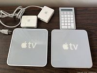 Top view of both Apple TV units, two power adapters, and numeric keypad