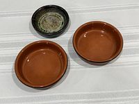 top view of two terracotta coasters and one stoneware dish