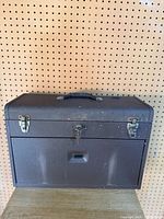 Front view of closed brown metal Craftsman toolbox with handle and latches