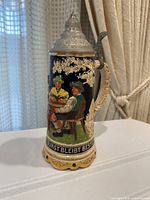 Front view of beer stein showing tavern scene and inscription