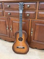 Full view front of acoustic guitar leaning against cabinet