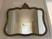 Full view of gold gilt Baroque wall mirror hanging on wall