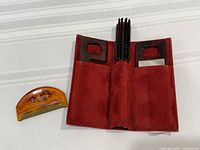 Open red case displaying comb, brush and mirror with sweater comb beside