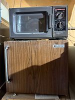 Microwave on top of mini fridge, frontal view