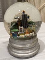 front angled view of snow globe showing mountain, city buildings and bridge