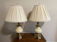 Front view of both matching brass and enamel table lamps with shades