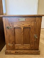 Front view of oak cabinet showing door, hinges, latch and nameplate